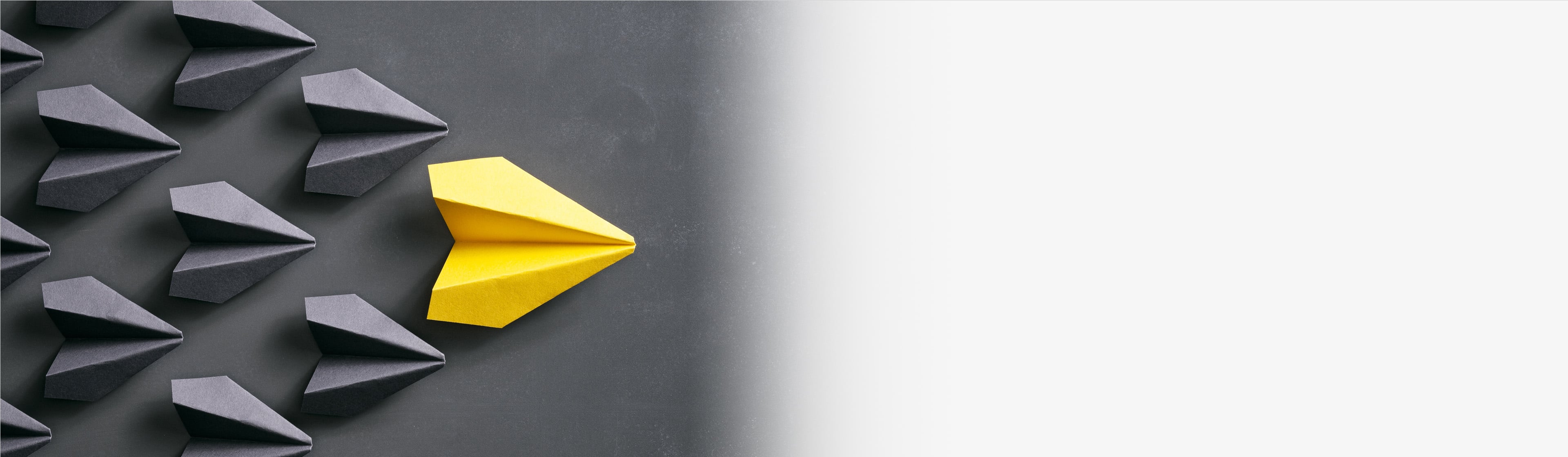Yello paper airplane in a pyramid with grey paper airplanes