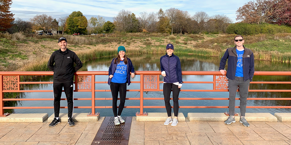 Four Baird associates standing on a bridge wearing Baird Cares t-shirts.