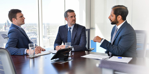 Three men sitting at a conference room table talking